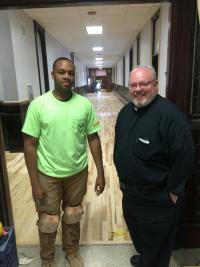 Jean Ribou, a worker with Floor Coverers Union Local 2168, is shown inside the Columbia campus of the St. John Paul II Catholic Academy last week. At right is Fr. Jack Ahern.  Photo by Bill Forry
